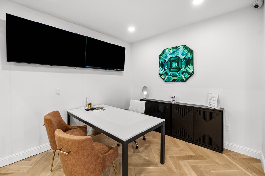 Modern office interior with dual screens, white desk, brown chairs, and vibrant wall art.