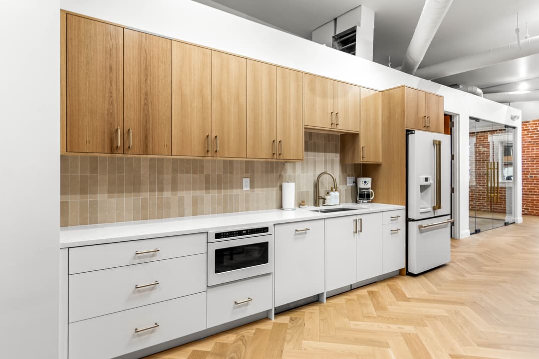 Modern kitchen with light wood cabinets, white counters, and stainless steel appliances.