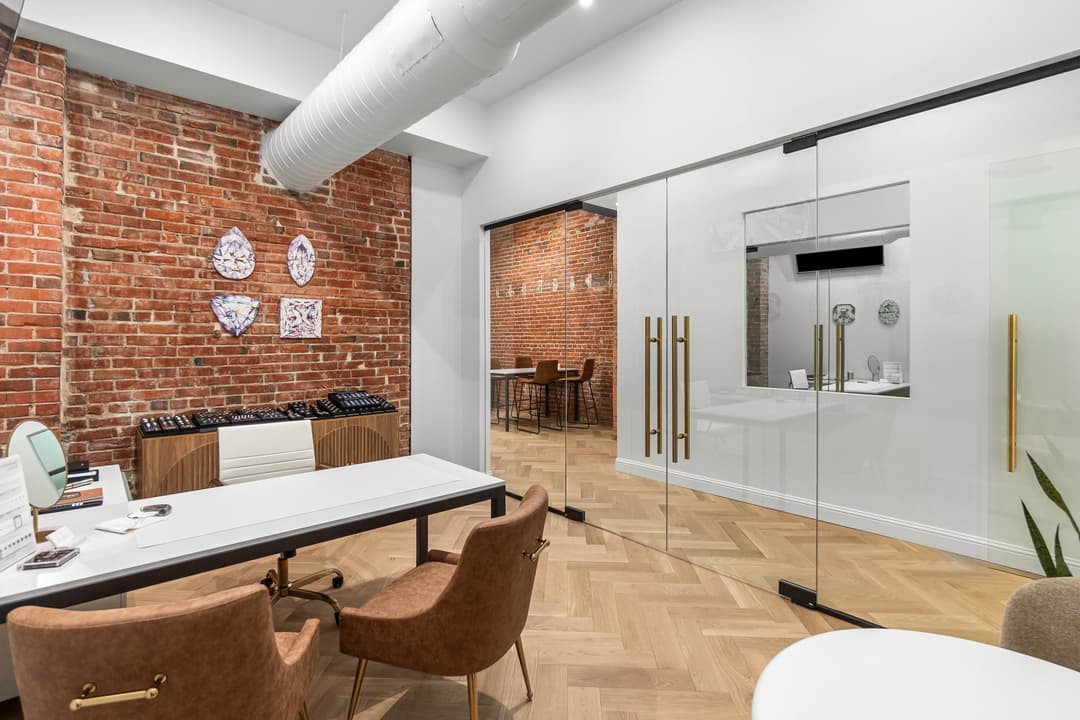 Modern office interior with exposed brick walls, glass partitions, and minimalist furniture.