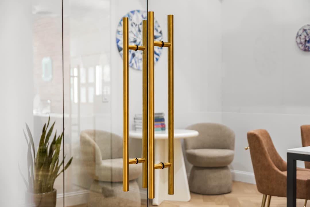 Brass door handles in a modern office with stylish chairs and a bright, inviting atmosphere.