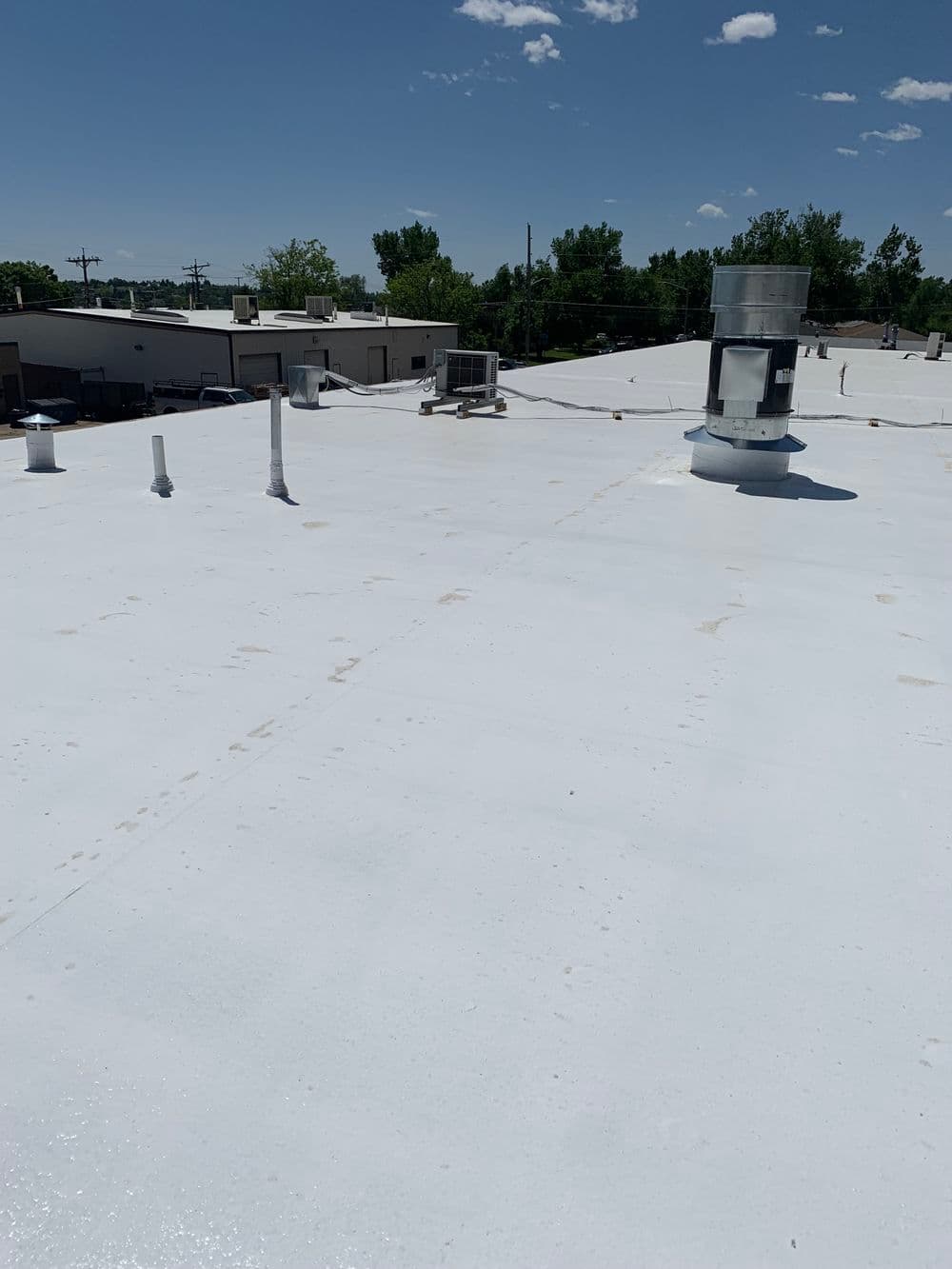 Flat commercial roof with ventilation system and clear blue sky. Ideal for roofing insights.