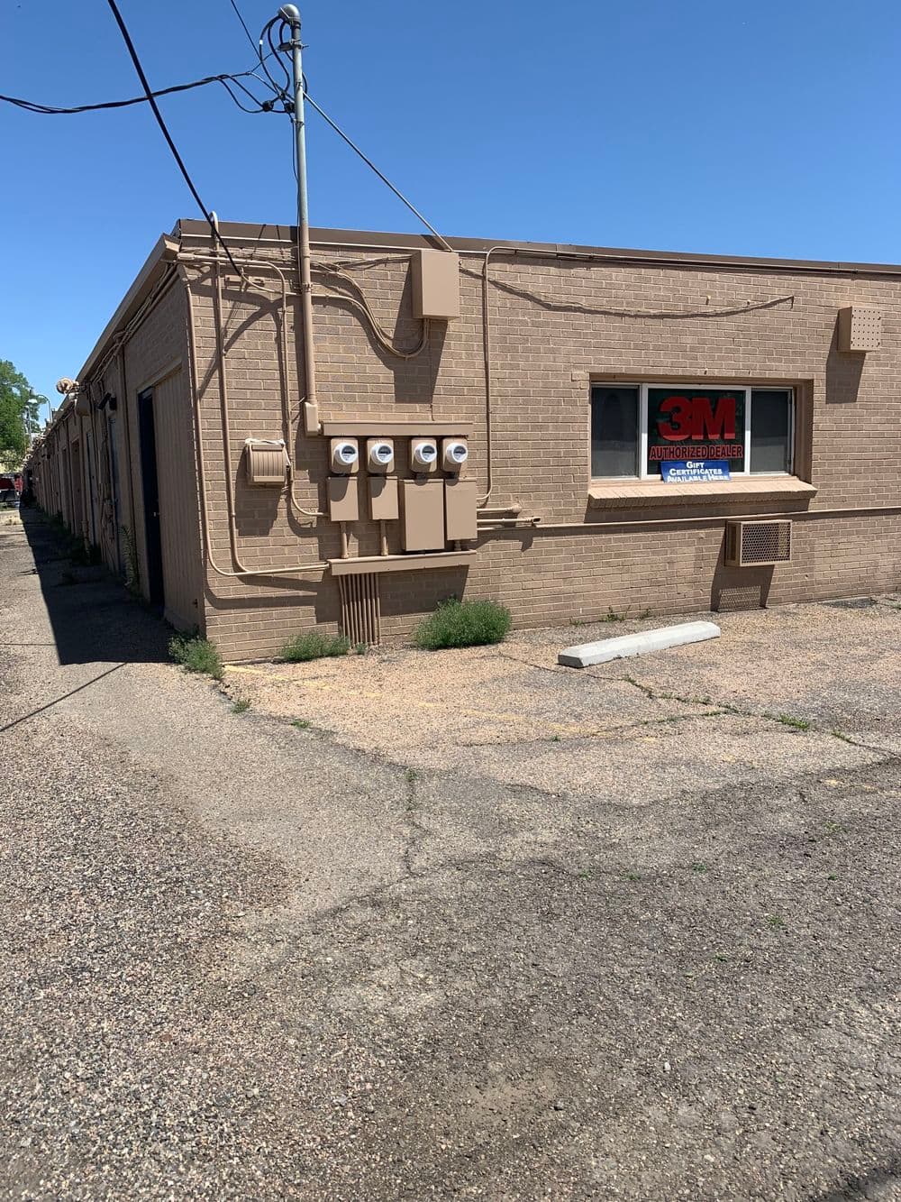 Brown building exterior with 3M signage and utility meters on the wall in clear weather.