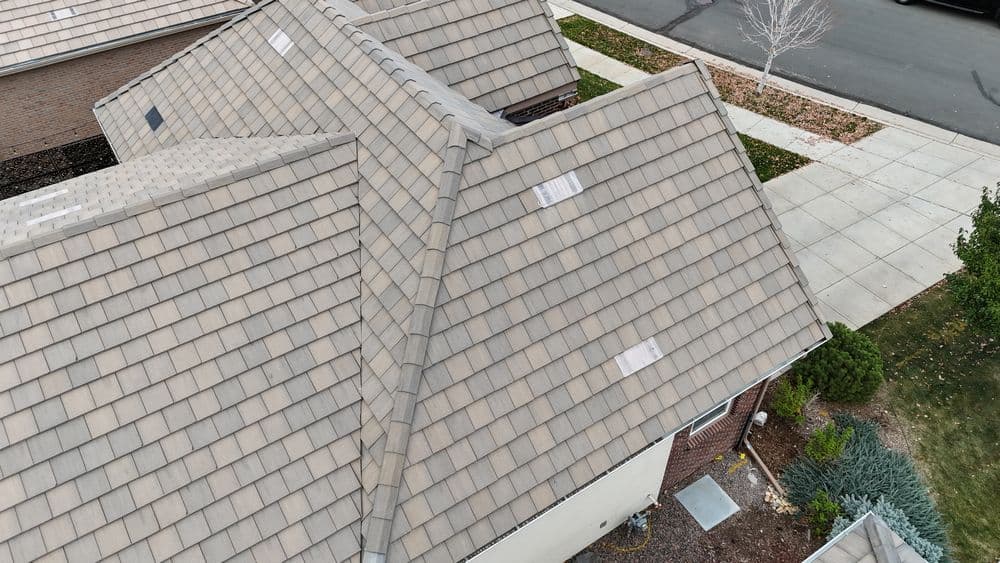 Aerial view of a residential roof showing shingles and roofing details in a suburban neighborhood.