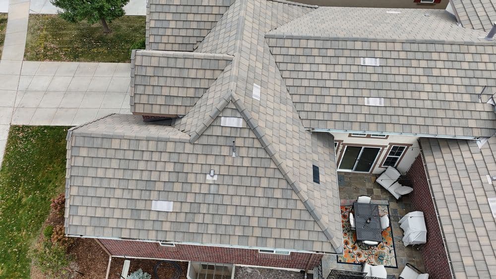 Aerial view of a home with a textured tile roof and patio furniture on a stone deck.