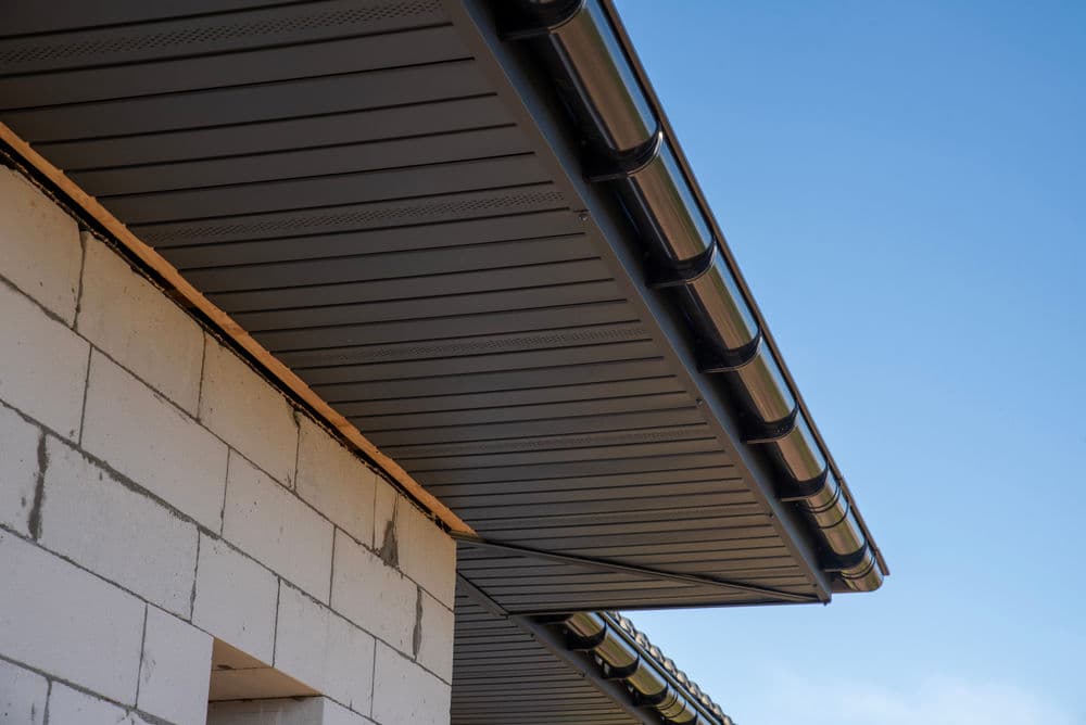 Modern roofing system with seamless gutters against a clear blue sky.