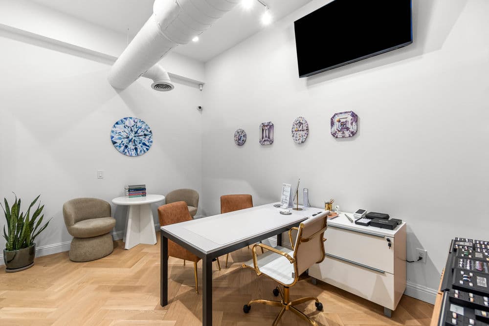 Modern office space featuring a desk, chairs, artwork, and minimalist decor, ideal for meetings.