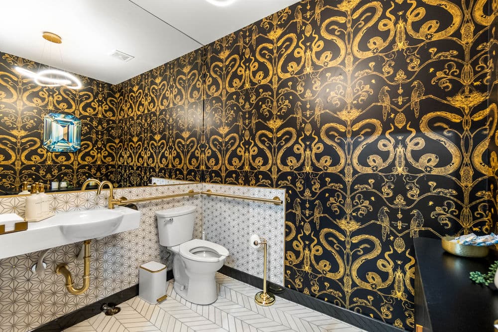 Luxurious bathroom with gold-patterned wallpaper, modern fixtures, and elegant design elements.